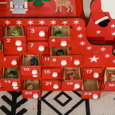 a red wooden christmas calendar sitting on top of a rug