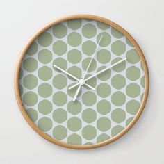 a green and white wall clock with circles on it's face, showing the time