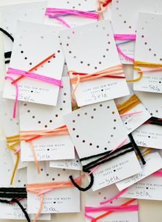 many different colored string attached to white cards with black and pink thread on them, all tied together