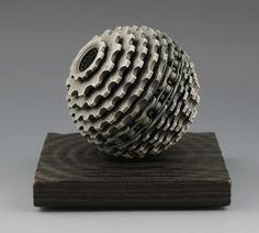 a metal object sitting on top of a wooden block in front of a gray background