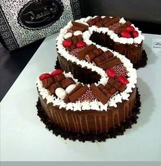 two cakes with chocolate frosting and cherries are on a white table next to a black box