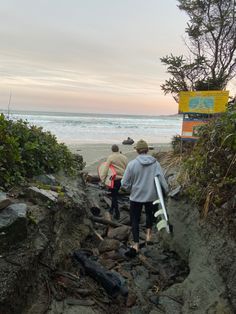 three people walking up some rocks near the ocean