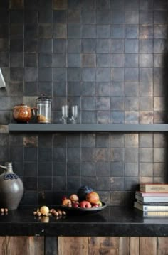 the kitchen counter is covered with books and bowls of fruit, along with two vases