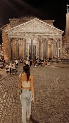 a woman is walking in front of an old building