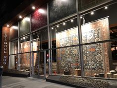 a store front with an intricately designed rug in it's glass windows at night