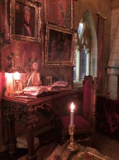 a candle is lit in front of an old desk with pictures on the wall behind it