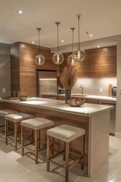 a modern kitchen with an island and bar stools in front of the countertop