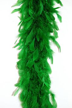 a green feather garland hanging on a white wall in the shape of a long column