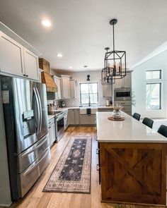 Add a modern farmhouse wood tray with black wire edging to the center of a large white kitchen island counter to match the dark wood cabinetry beneath and complement the rustic vibe of the room. Place a clear glass bottle on the tray with wheatgrass for a neutral look...   Image: the_hoffman_homestead