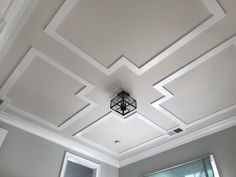 the ceiling in this living room is painted white and has geometric designs on it, with a chandelier hanging from the ceiling