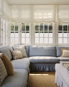 a living room filled with lots of furniture and windows covered in white drapes