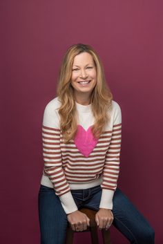 a woman sitting on top of a stool with a pink heart in the middle of her chest