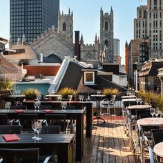 an outdoor dining area with tables, chairs and umbrellas on the roof of a building