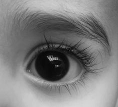 an eye with long eyelashes is shown in black and white