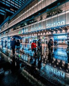 people are walking in the rain at shinju station on a rainy night with umbrellas