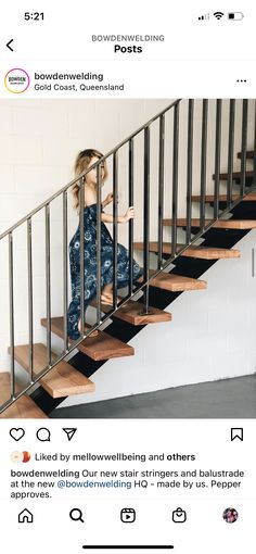 a woman sitting on top of a stair case next to a hand rail and stairs