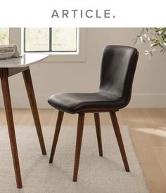 a black chair sitting next to a wooden table on top of a white carpeted floor