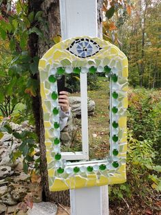 a yellow and white mirror sitting on top of a wooden pole next to a tree