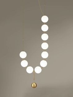 three lights hanging from the ceiling with white balls on each one and a gold ball at the end