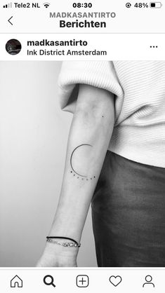 a black and white photo of a woman's arm with a small crescent tattoo on it