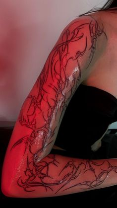 a woman's arm with tattoos on it and red light coming from behind her