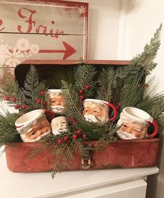 an old suitcase filled with christmas ornaments and greenery on top of a dresser next to a sign