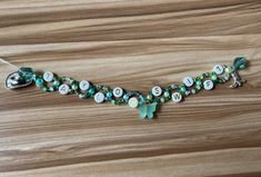 a beaded necklace with green and white beads on a wooden table next to an earring