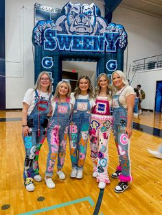 four girls in overalls standing on a basketball court