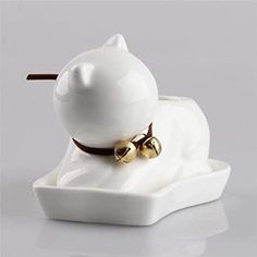 a white ceramic cat figurine with bells on its neck