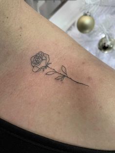 a rose tattoo on the back of a woman's shoulder