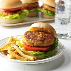 there is a burger and french fries on the plate next to some water bottles in the background