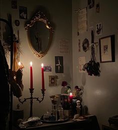 a table with candles and pictures on the wall in a dimly lit room next to a mirror