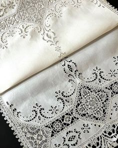 two white tablecloths with black lace on them are laying next to each other