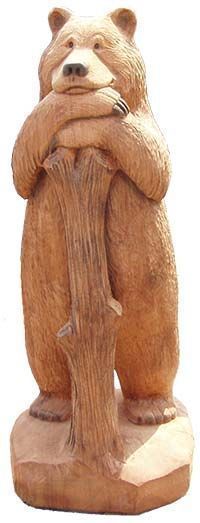 a wooden statue of a bear holding its head on top of a tree stump with his arms crossed