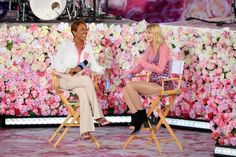 two women sitting on chairs in front of a floral wall with pink and white flowers