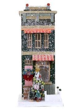 a doll house with a christmas tree in front of it