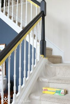 a white staircase with yellow handrails next to a blue wall and carpeted stairs