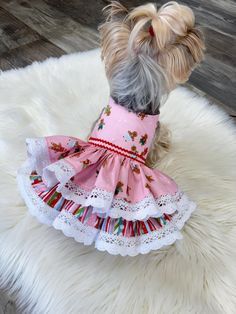 a small dog wearing a pink dress on top of a white rug