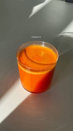 an orange juice in a plastic cup on a white surface