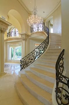 an elegant staircase with chandelier and marble floors