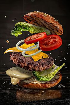 a hamburger falling into the air with lettuce, tomato and onion on it