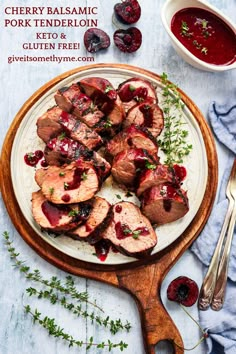 meat with cranberry sauce on a white plate next to silverware and fork