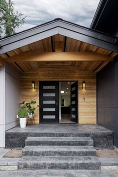 the entrance to a house with steps leading up to it and potted plants on either side