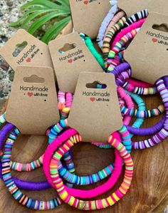 several colorful bracelets sitting on top of a wooden table next to a potted plant