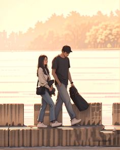 two people are walking along the water with their bags in hand and one person is carrying luggage