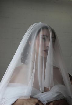 a woman wearing a white veil with her hands on her chest and the back of her head