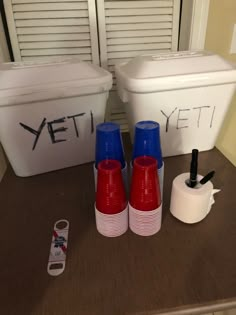 two plastic containers with lids and cups sitting on a counter top next to toilet paper