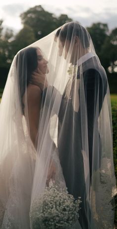 a bride and groom kissing under a veil