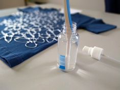 an empty bottle with a toothbrush in it on a table next to a blue towel