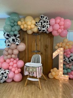 a baby's first birthday party with balloons and cow print decorations on the wall